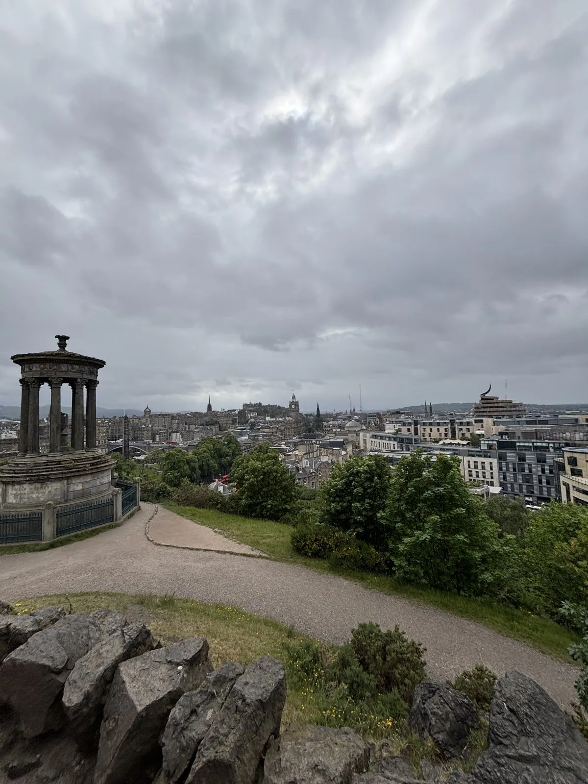 City overview featuring a stone monument in the foreground under cloudy skies.