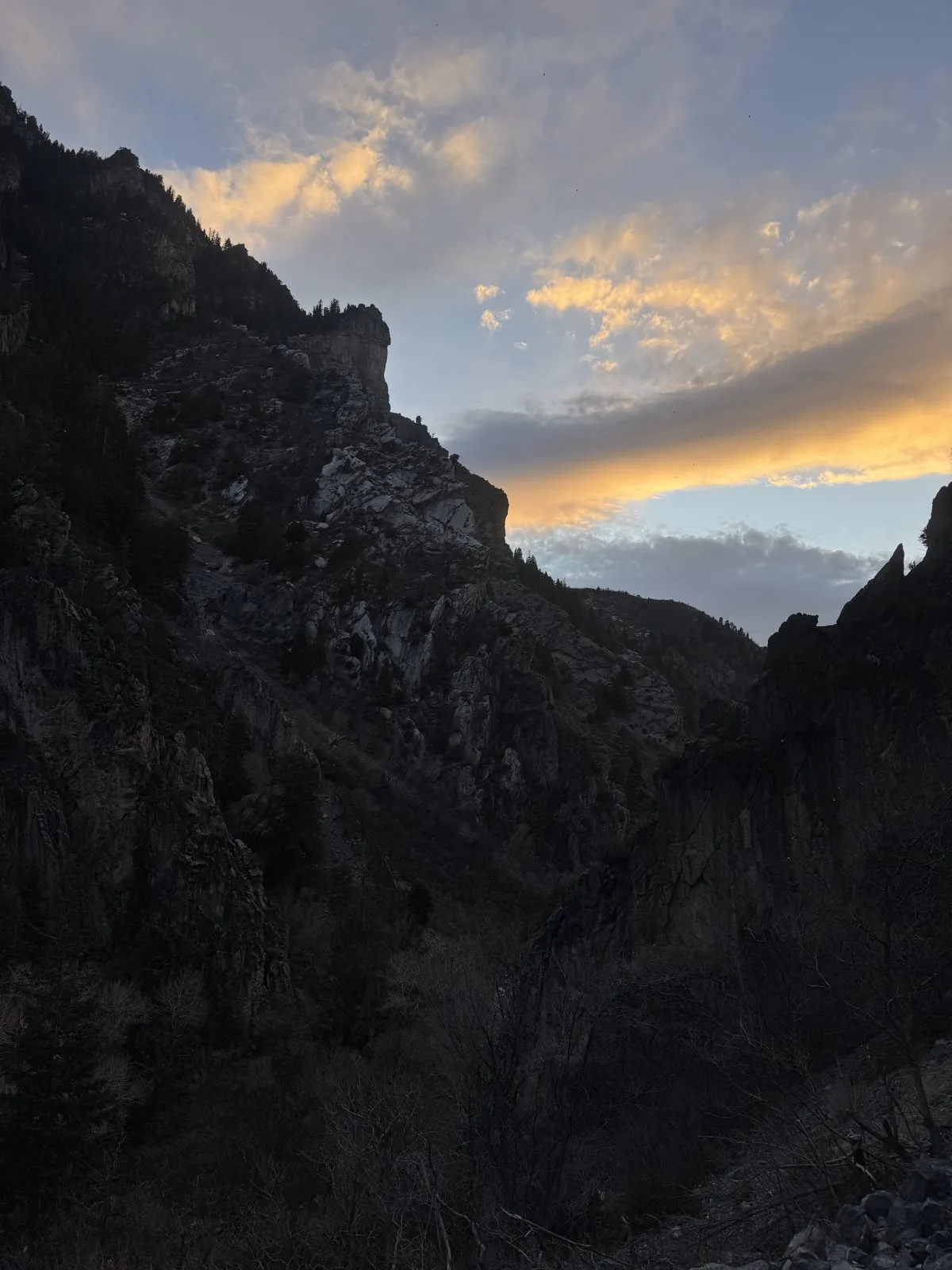 A canyon ridge at sunset with warm orange light across the sky.