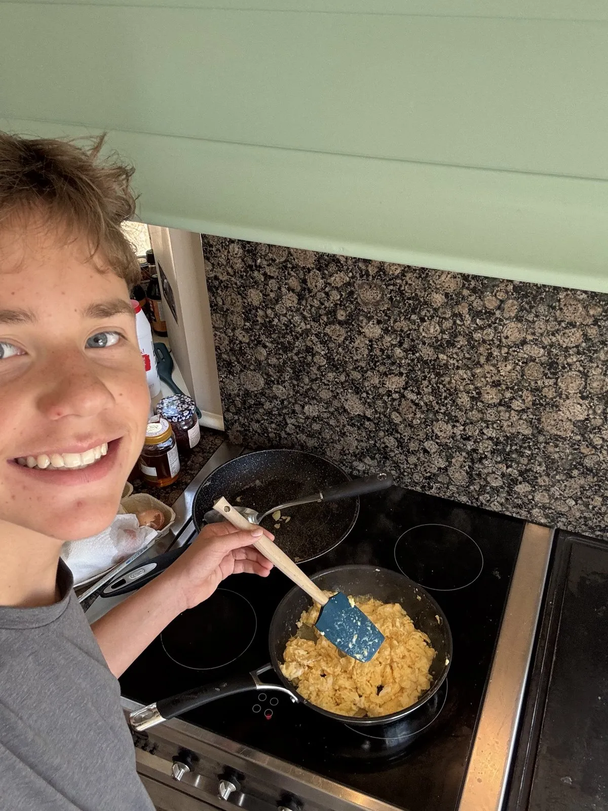 Scrambled eggs cooking in a frying pan on an electric stovetop.